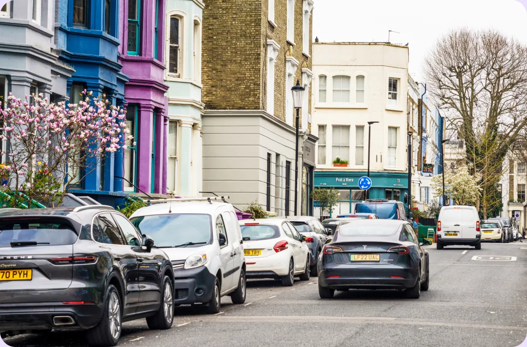 Cars parked along a residential street lined with colourful terraced houses